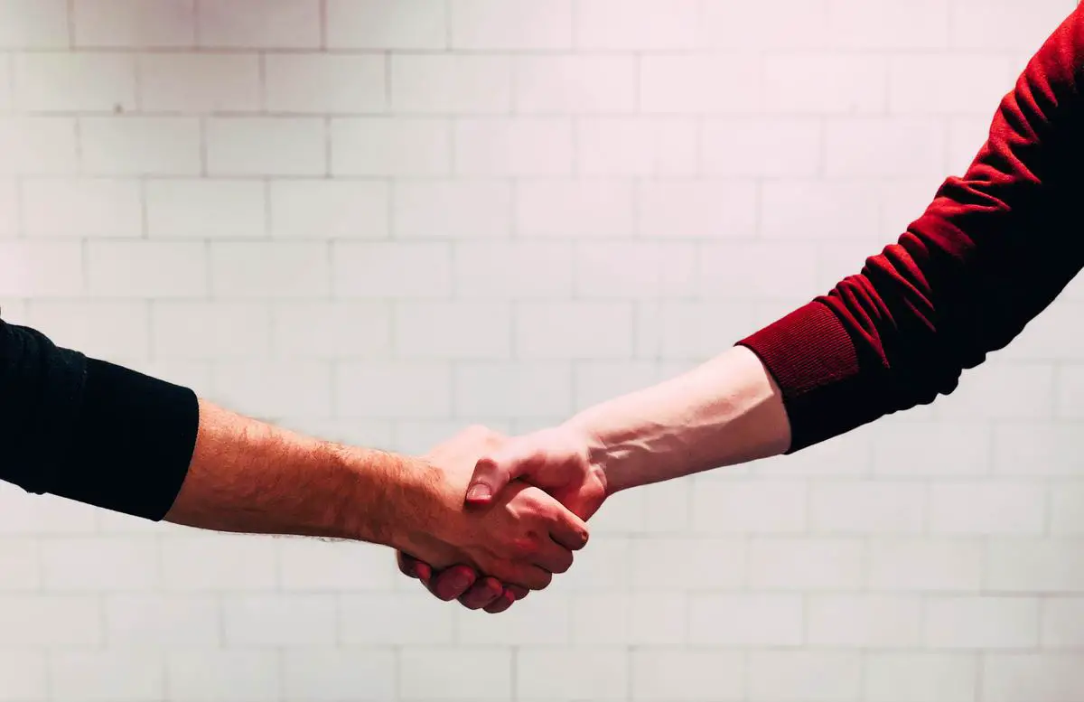 Illustration of two hands shaking to symbolize behavioral leadership in action